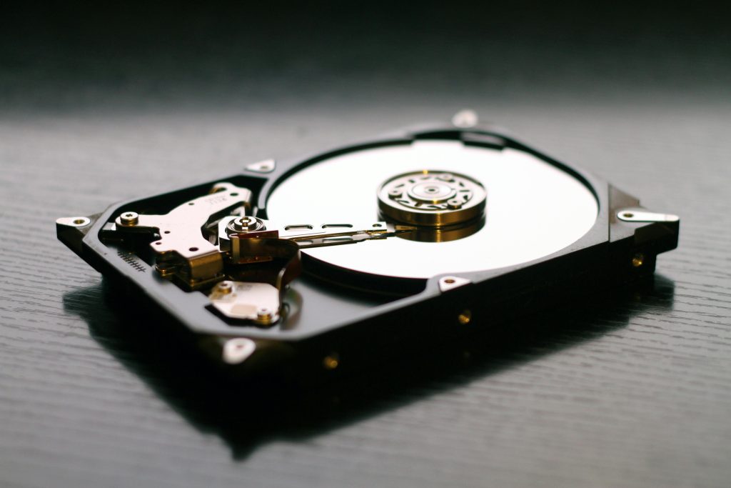 pexels-photo-117729-117729 An open hard drive is displayed on a wooden surface, showcasing its internal components and metallic details.