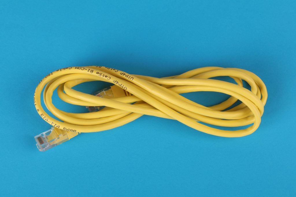 pexels-photo-3541555-3541555 High-angle view of a yellow ethernet cable on a bright blue background.